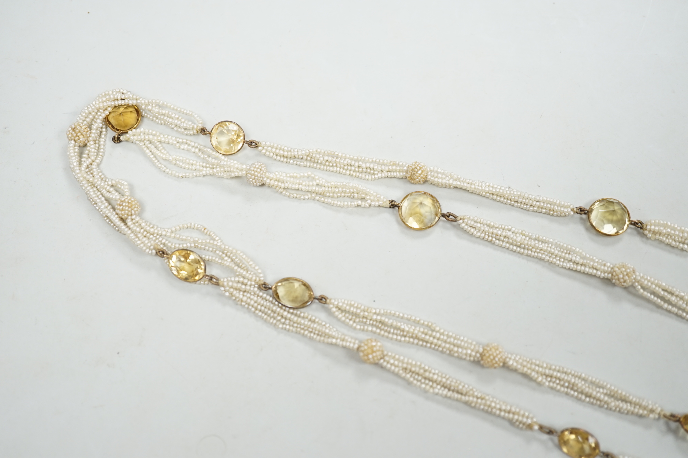 A 19th century Indian multi strand seed pearl and oval cut citrine set long necklace, with gem set tassel drops, 166cm.